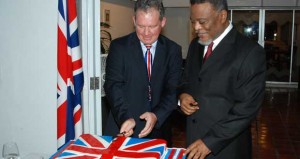 Prime Minister, Samuel Hinds awaits his turn as British High Commissioner Andrew Ayre has the first go at cutting the traditional birthday cake in celebration of Queen Elizabeth II’s 88th birthday. [Guyana Chronicle Photo]